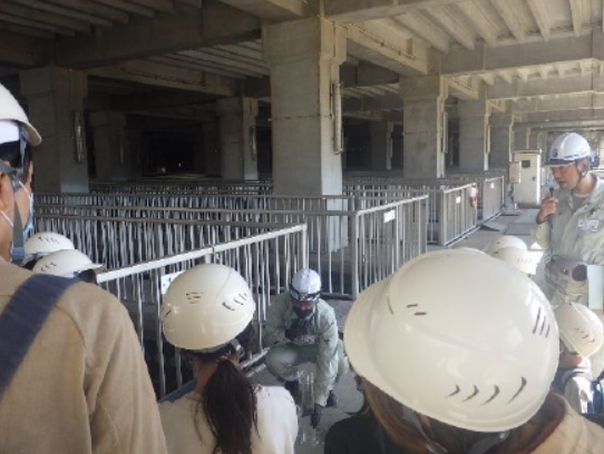 施設見学する親子２名と説明する職員